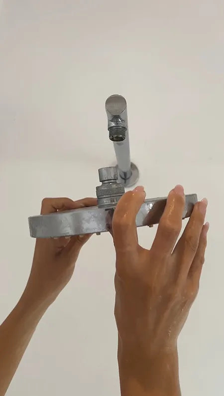Hands installing or adjusting a showerhead in a bathroom.