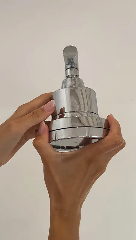 Hands holding a shiny, metallic, cylindrical object with a lever at the top.