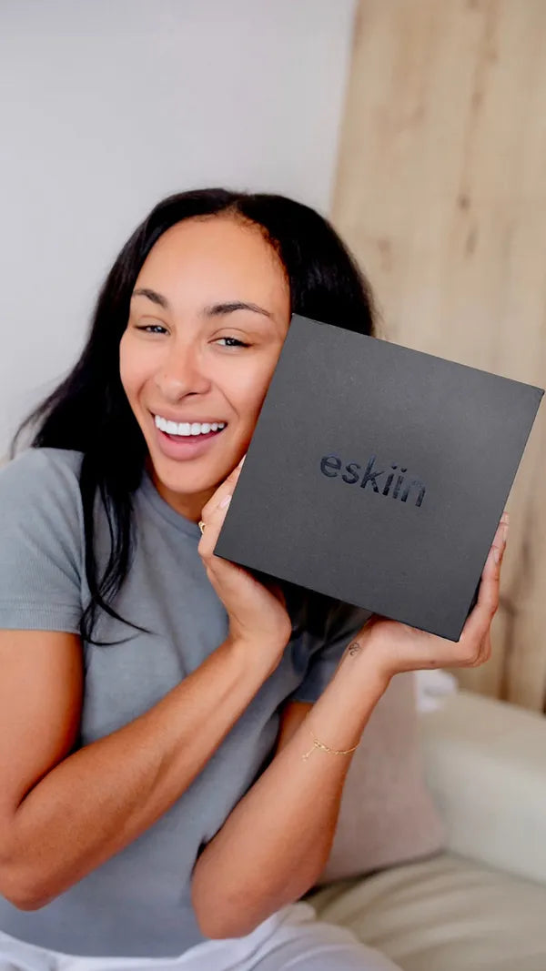 Woman smiling and holding a black box labeled 'eskiin'.